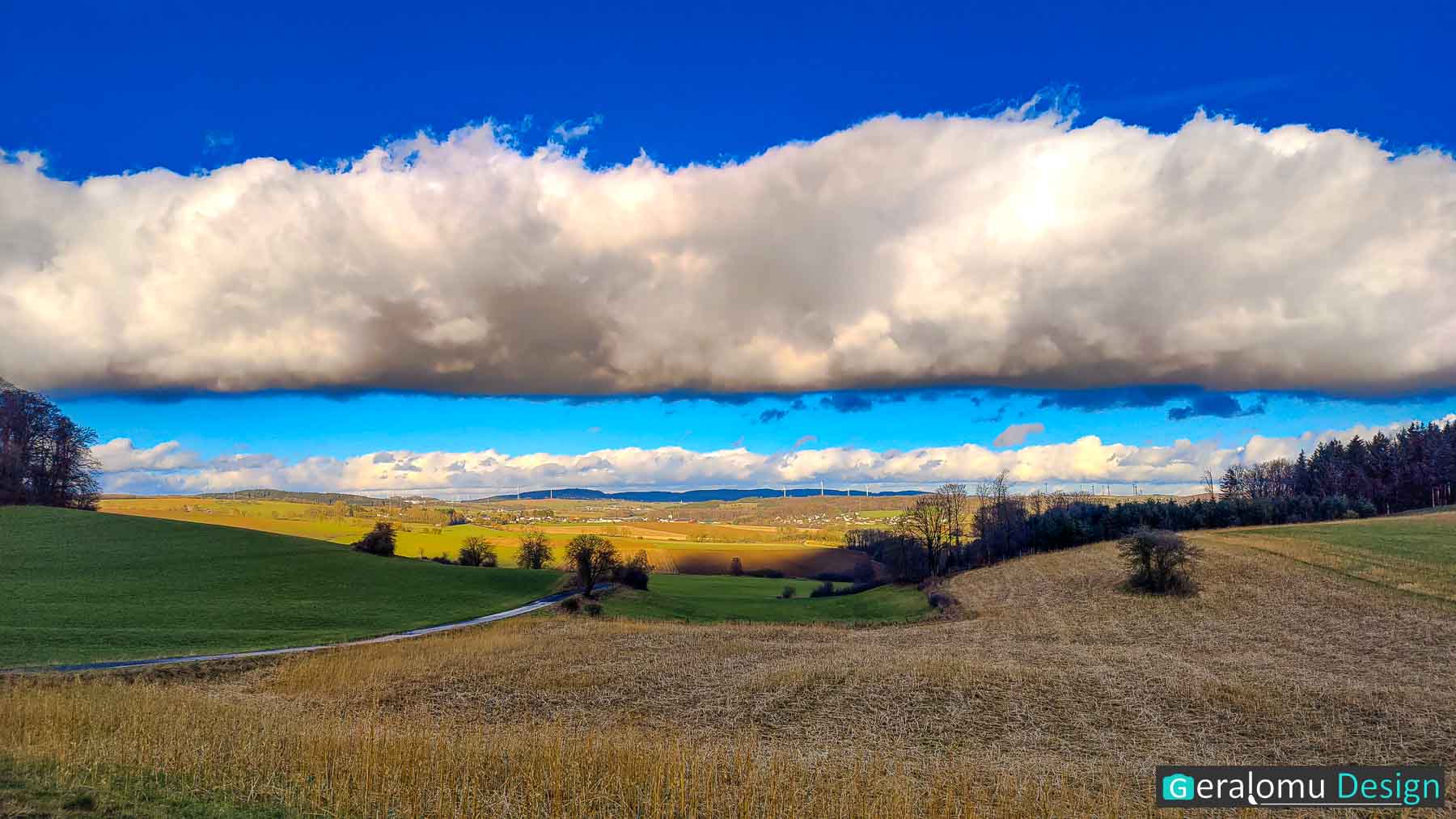 Diese Landschaftsfotografie zeigt eine Rommersheimer Landschaft, beleuchtet von strahlender Sonne, jedoch unter einer dichten Wolkendecke.